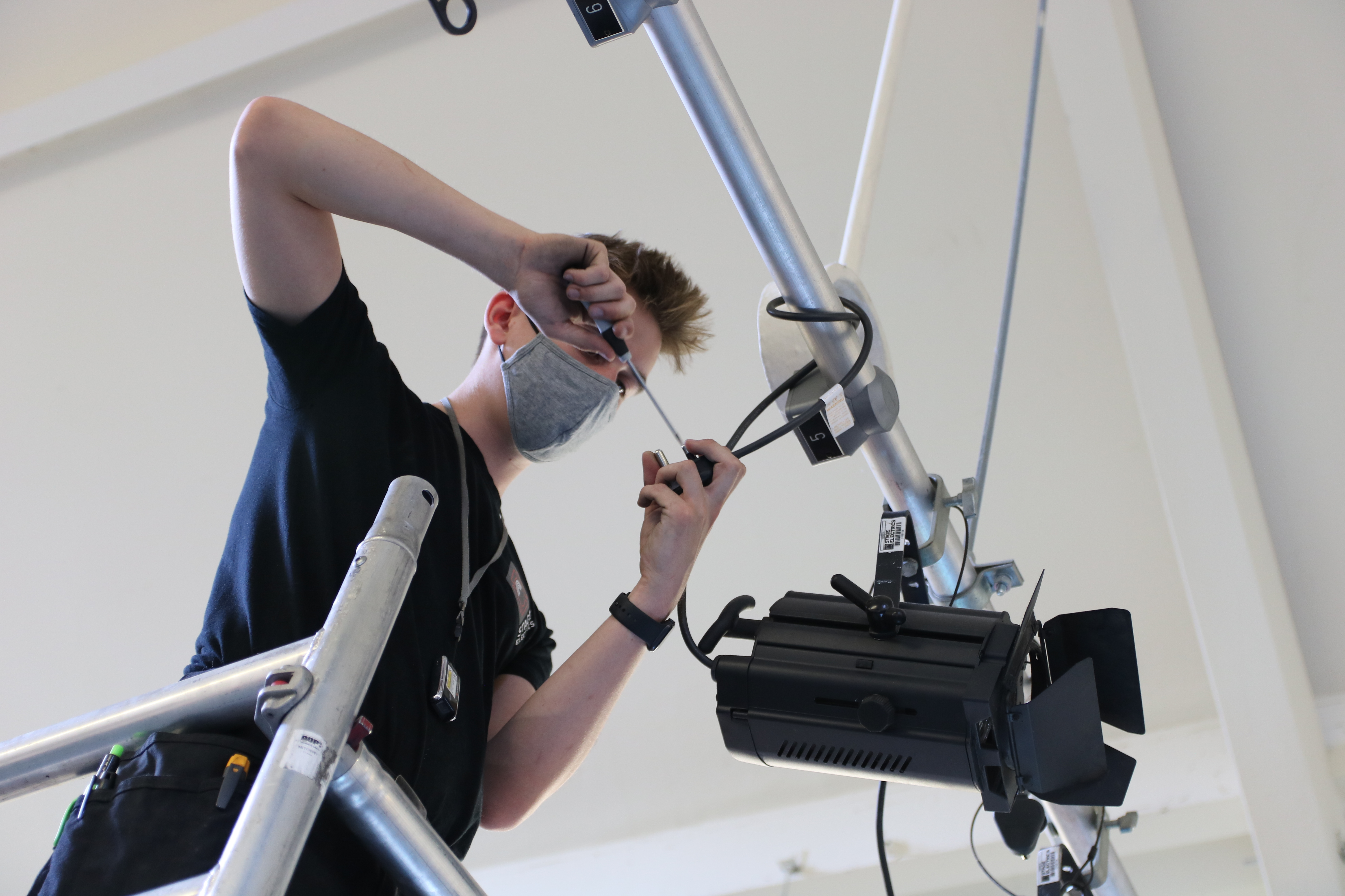 A professional stage technician safeguarding a fresnel with barndoor